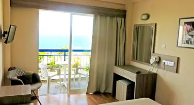 a living room with a room with a fireplace and a balcony at Marina Hotel in Ayia Napa