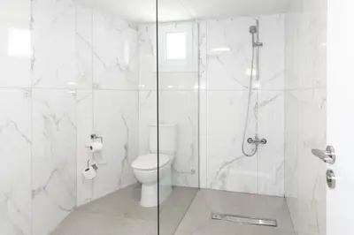 a white bathroom with a shower and a toilet at Blazer Residence in Larnaka