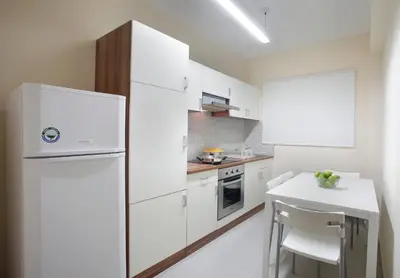 a white kitchen with a refrigerator and a table at Lordos Hotel Apartments Nicosia in Nicosia