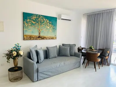 a living room with a couch and a tree painting on the wall at Eleonora Hotel Apartments in Larnaka