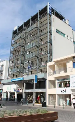 a tall white building with a lot of windows at Eleonora Hotel Apartments in Larnaka