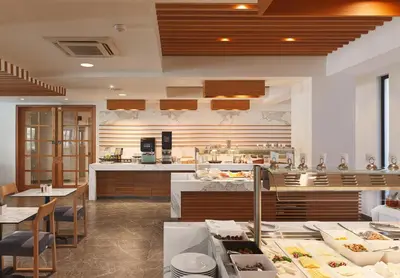 a restaurant with tables and chairs and a kitchen at Pefkos City Hotel in Limassol