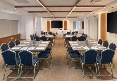 a conference room with tables and chairs and a projection screen at Pefkos City Hotel in Limassol