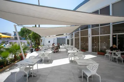 a patio with tables and chairs and people sitting on it at Papouis Protaras Hotel in Protaras