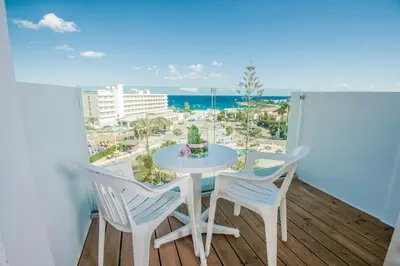 a table and chairs on a balcony with a view of the beach at Alva Hotel Apartments in Protaras