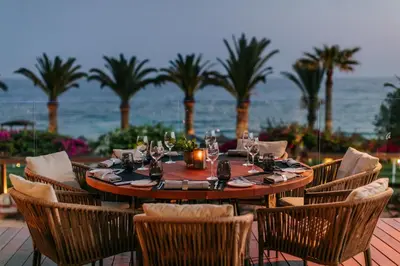 a wooden table with chairs and a table with the ocean at Alion Beach Hotel in Ayia Napa