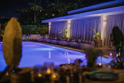 a swimming pool at night with tables and chairs at Alion Beach Hotel in Ayia Napa