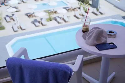a table with a drink on it next to a pool at Kapetanios Bay Hotel Protaras in Protaras