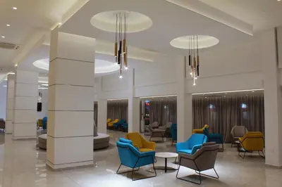 a lobby with blue and yellow chairs and tables at Kapetanios Bay Hotel Protaras in Protaras