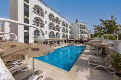 a swimming pool with chairs and umbrellas next to a building at Cactus in Larnaka