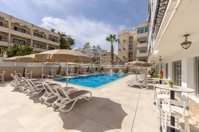 a swimming pool with lounge chairs and a table and umbrella at Cactus in Larnaka