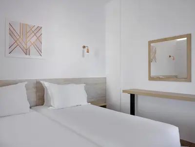 a bedroom with two beds and a mirror on the wall at Atlantica Panthea Resort in Ayia Napa