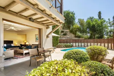 an outdoor patio with a pool and a house at Columbia Beach Resort in Pissouri