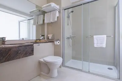 a bathroom with a toilet and a glass shower at Golden Bay Beach Hotel in Larnaka
