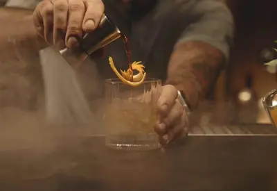 a man is making a drink in a glass at The GrandResort - Leonardo Limited Edition in Limassol