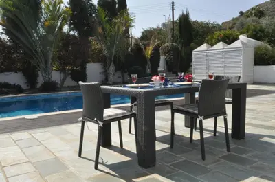a table and chairs on a patio next to a pool at Katikies 22 in Pissouri
