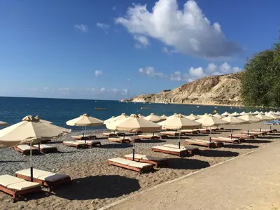 a group of umbrellas and lounge chairs on a beach at Katikies 22 in Pissouri