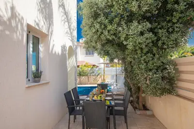 a table and chairs on a patio with a tree at George's Lux Villa in Protaras