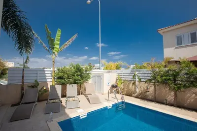 a swimming pool with lounge chairs next to a house at George's Lux Villa in Protaras