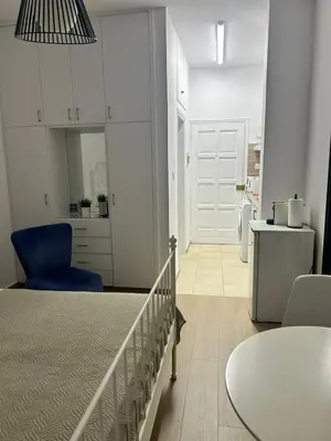 a bedroom with a bed with a blue chair and a table at Harmony Studios in Larnaka