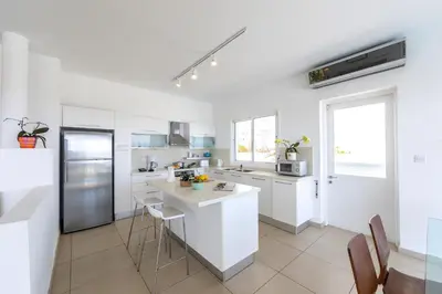 a white kitchen with white cabinets and a counter at Protaras Beachfront Villa Alia in Protaras