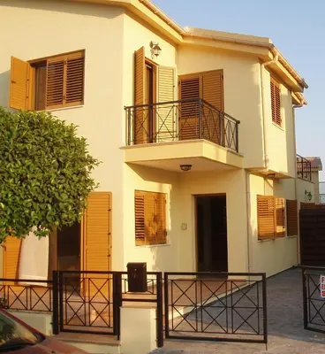 a white building with brown shutters and a balcony at Alkinoou Residence in Limassol