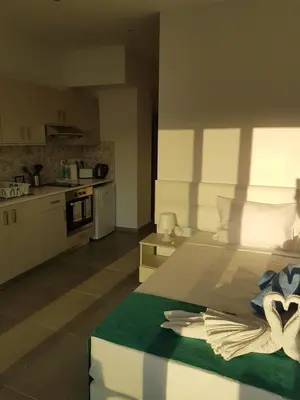 a bedroom with a large bed and a kitchen at Christopher's Sandy Beach Suites in Ayia Napa