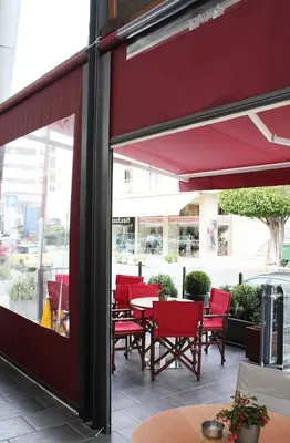 a group of red chairs and tables outside a restaurant at Manolia City Residences in Nicosia