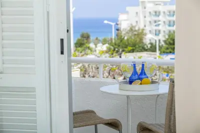 a table with bottles and glasses on a balcony at Protaras Central Sunrise in Protaras