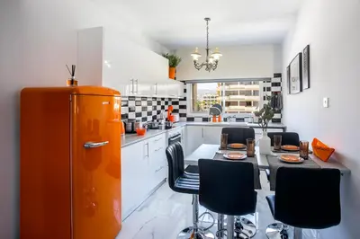 a kitchen with an orange refrigerator and a table with chairs at Castle Holiday Apartments in Limassol