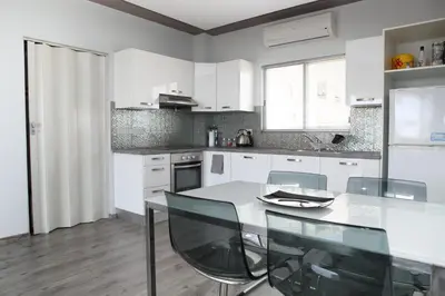 a white kitchen with a table and chairs in it at Salt Lake view Apartment in Larnaka