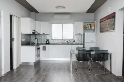 a kitchen with white cabinets and a glass table at Salt Lake view Apartment in Larnaka