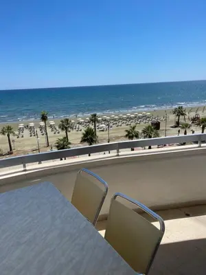 a balcony with a table and two chairs and the beach at Alex Beach Apartment 31 in Larnaka