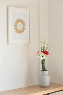 a vase of flowers on a table with a picture at SeaBreeze Villas by TrulyCyprus in Ayia Napa