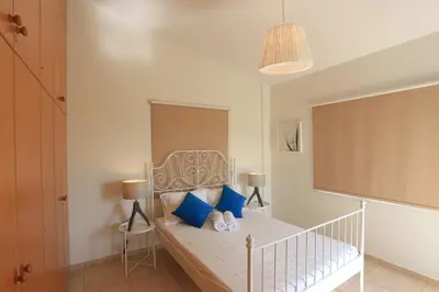 a bedroom with a white bed with blue pillows at SeaBreeze Villas by TrulyCyprus in Ayia Napa