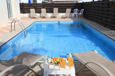 a pool with chairs and a table with fruit on it at SeaBreeze Villas by TrulyCyprus in Ayia Napa