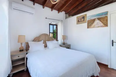 a white bedroom with a bed and a window at Meleni Cottage Houses in Parekklisha