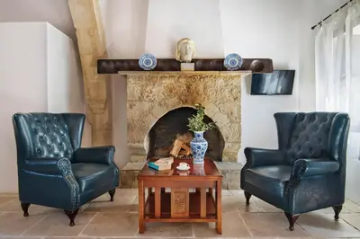 two chairs and a table in a living room with a fireplace at Meleni Cottage Houses in Parekklisha