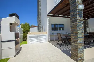 a patio with a grill and a table with chairs at Protaras Villa Anemoni 6 in Protaras