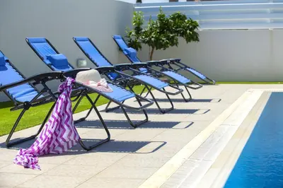 a row of blue chairs next to a swimming pool at Protaras Villa Anemoni 6 in Protaras
