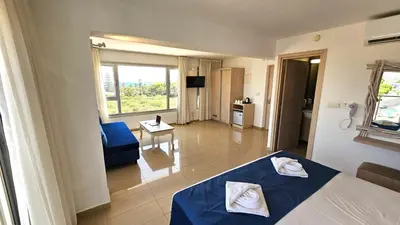 a bedroom with a blue bed and a living room at NissiLant hotel & suites in Ayia Napa