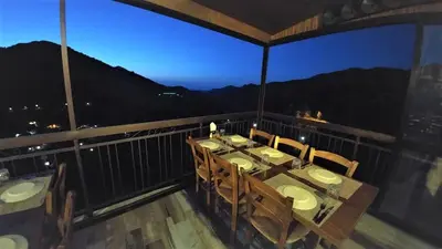 a dining room with a table and chairs on a balcony at Perneia Rooms in Askas