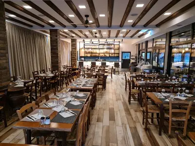 a dining room with wooden tables and chairs at Perneia Rooms in Askas