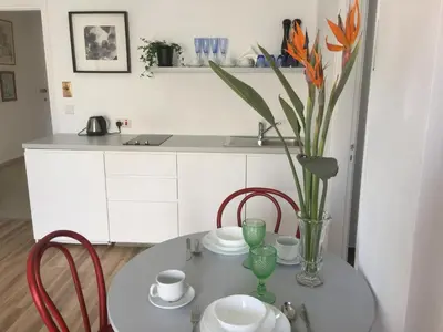 a table with chairs and a vase with flowers on it at Pasithea Holiday Apartments in Larnaka
