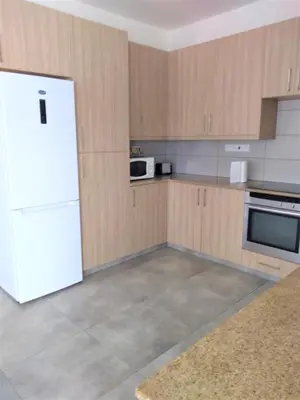 a kitchen with a white refrigerator and wooden cabinets at T&E Villa in Larnaka