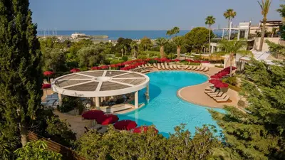 a swimming pool with chairs and umbrellas in a resort at St Raphael Resort in Limassol