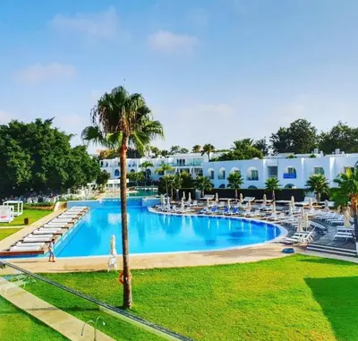 a large swimming pool with chairs and a palm tree at So Nice Beach Resort in Ayia Napa