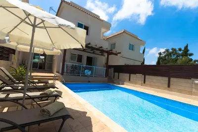a swimming pool with two chairs and an umbrella next to a house at myExclusiveVilla 683 in Protaras