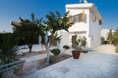 a white house with trees in front of it at Fig Tree Bay Villa 2 in Protaras