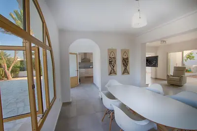 a white dining room with a table and chairs at Fig Tree Bay Villa 2 in Protaras